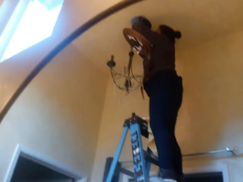 Electrician installing a chandelier in a Lake Worth residence